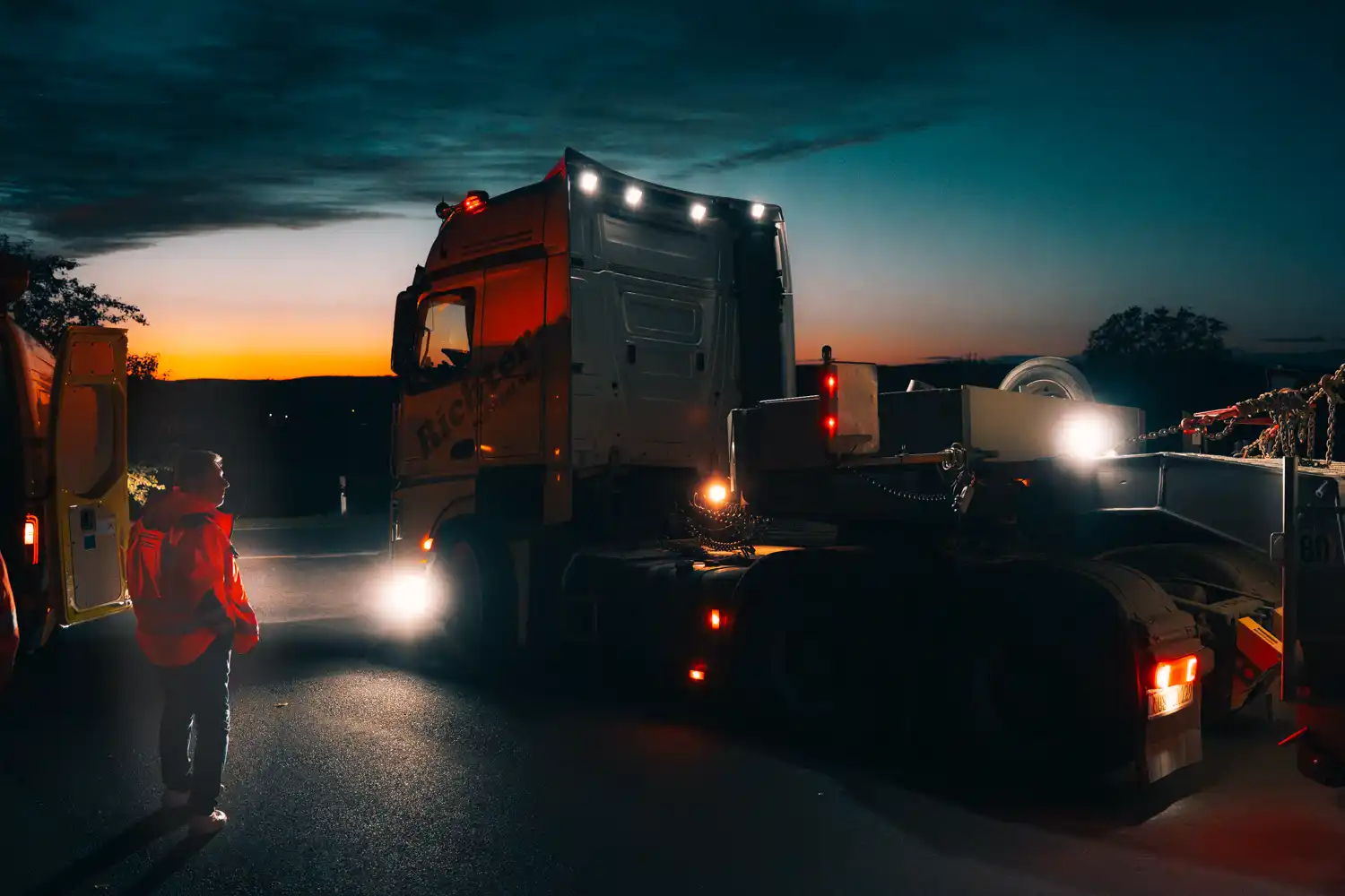 Schwertransport von Richter am Abend mit Mitarbeiter im Vordergrund